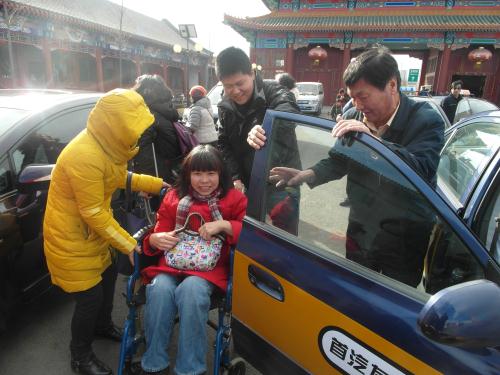 志愿者协助残疾朋友从爱心车上下来