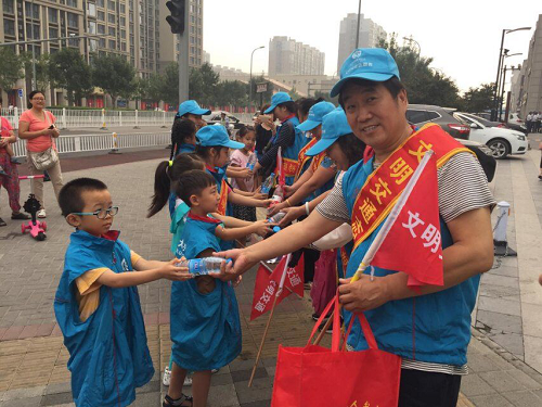 小志愿者为文明交通志愿者递上矿泉水2