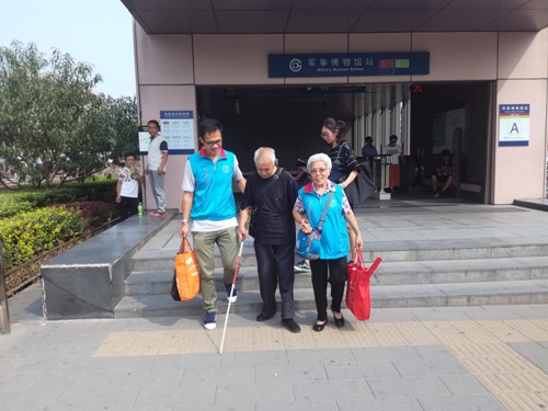 志愿者在地铁接盲人带到演出现场