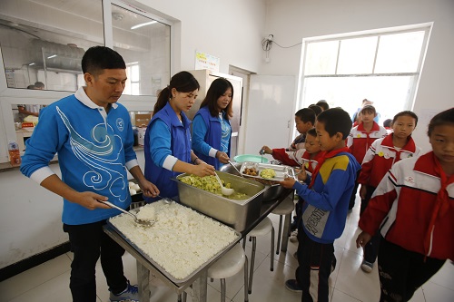 志愿者为孩子们发放营养午餐
