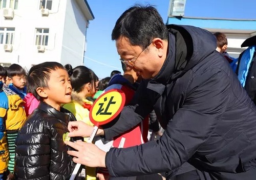 志愿者给小学生佩戴文明小贴纸
