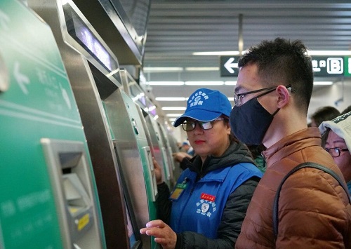 2 志愿者在北土城站区TVM机前为旅客服务