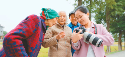 　参与公益摄影活动的海盐供电红船青年志愿者向老人们展示照片。