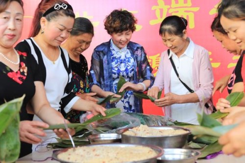 02天府新区合江街道的志愿者教居民包粽子。图据 天府新区文明办
