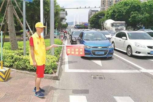 　在市第一人民医院附近的十字路口，志愿者配合交警疏导交通和引导行人文明出行。