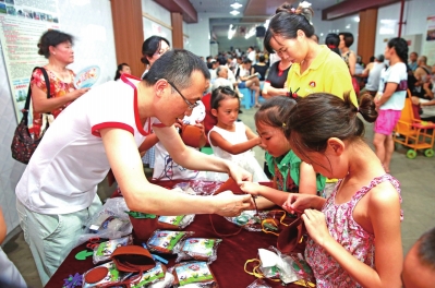 “爱心赶场天”活动现场，志愿者教孩子制作手工艺品　渝北时报 记者 胡瑾　摄