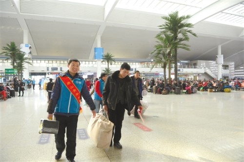 春运期间，青年志愿者在铁路唐山站帮旅客拿行李