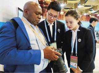 02志愿者为非洲记者解答图片下载的技术问题。