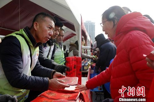 年货市集中，义工为现场观众发放春联。李佩珊 摄