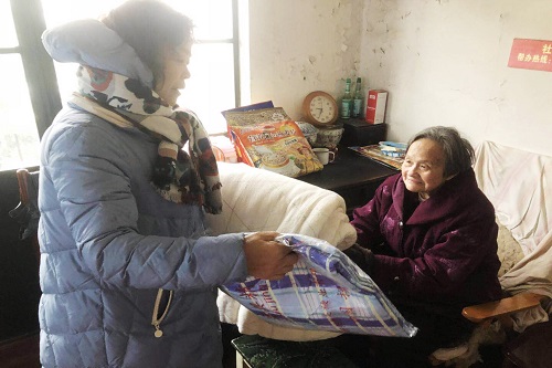 志愿者给独居老人送棉被。图片来源：扬州晚报