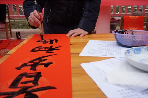 活动现场，文化志愿者挥毫泼墨，为村民们写春联、送福字，把满满的祝福赠送给当地村民。王媛 摄