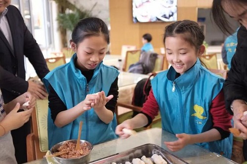 小志愿者们为爷爷奶奶们包饺子。图片来源：琴香缘爱乐社