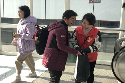 志愿者在动车站帮助旅客。